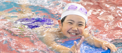 泳ぎながらピースをする子供